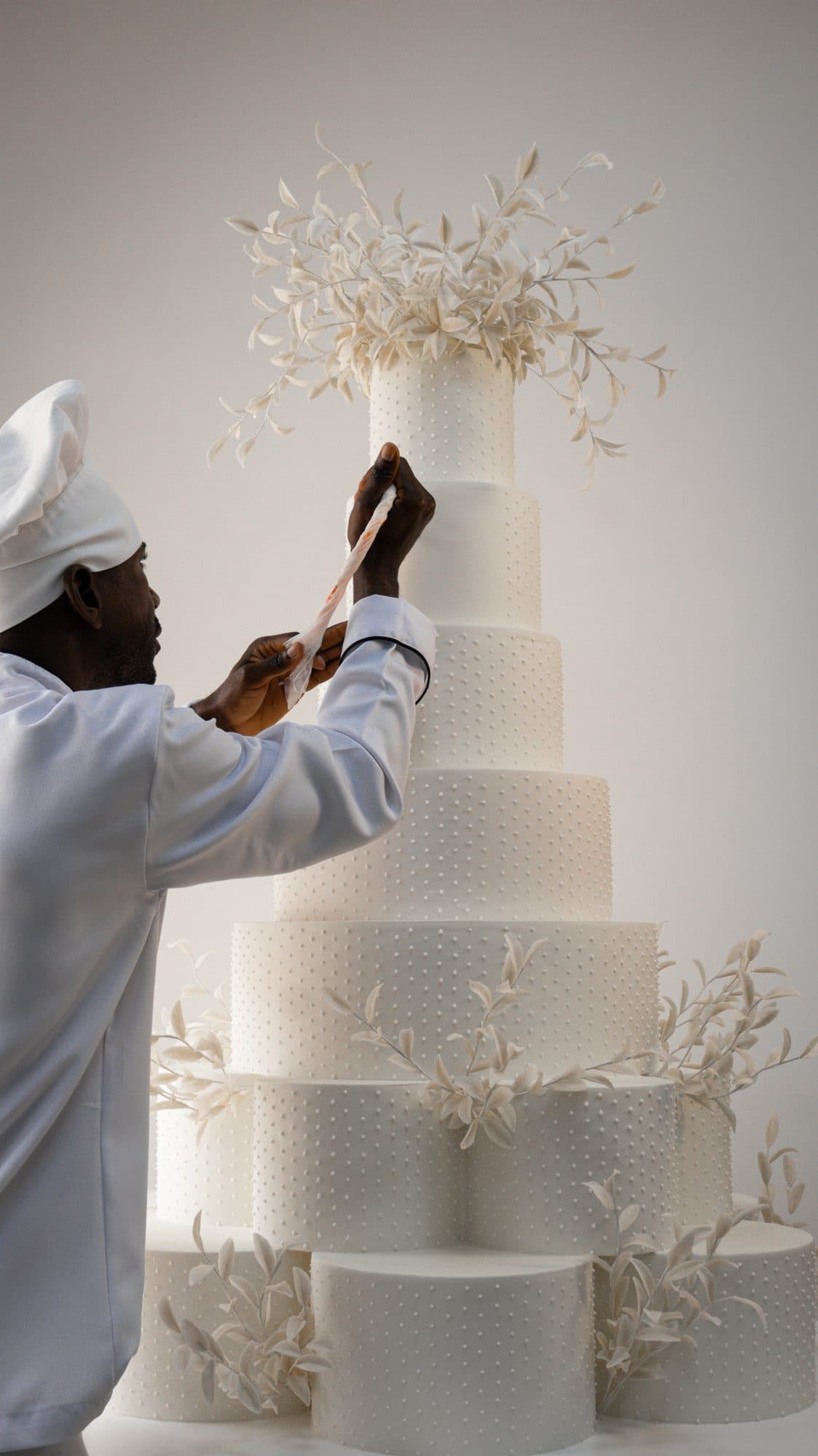 Pasteleiro a decorar um bolo branco de vários andares